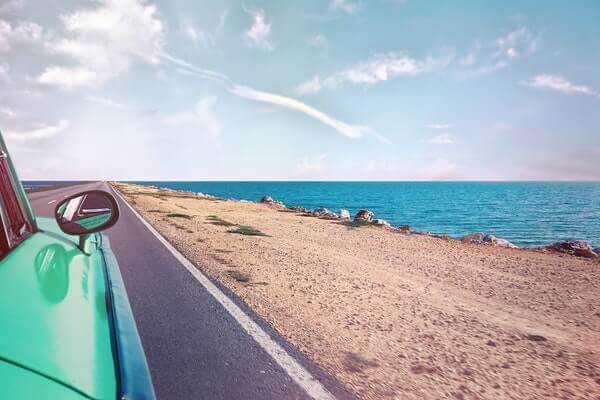 green-car-near-seashore-with-blue-ocean